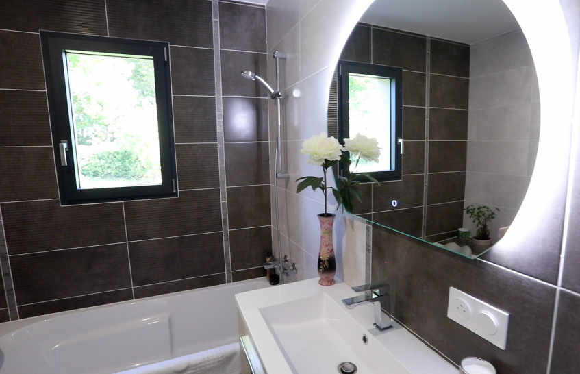 Salle de bain moderne avec carrelage noir et miroir lumineux